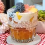 A glass of mango sago dessert with cream cheese mix and pomelo.