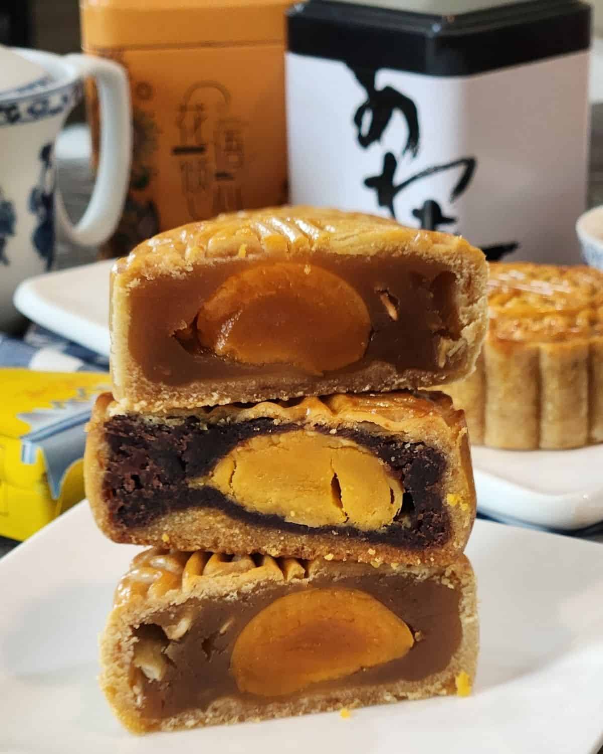 Three sliced mooncakes stacked on a plate.
