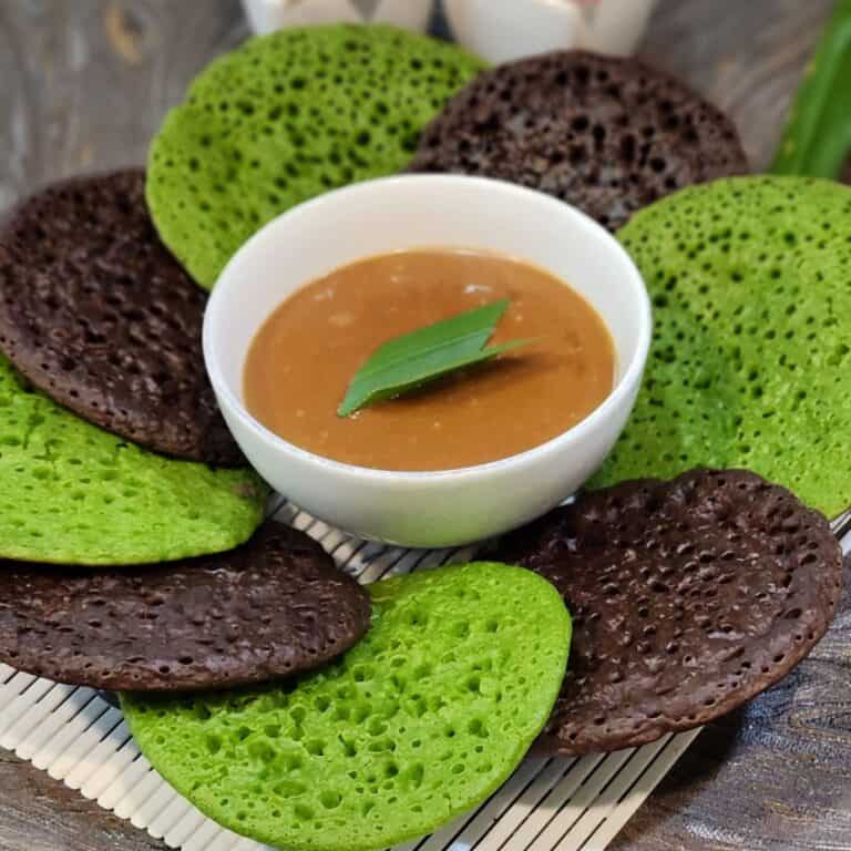 A few serabi pandan pancakes arranged on a plate with the coconut milk sauce in the center.