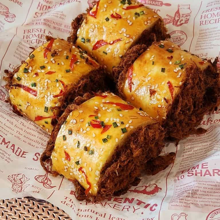 Four beef floss bread roll (roti gulung abon) served on a parchment paper.