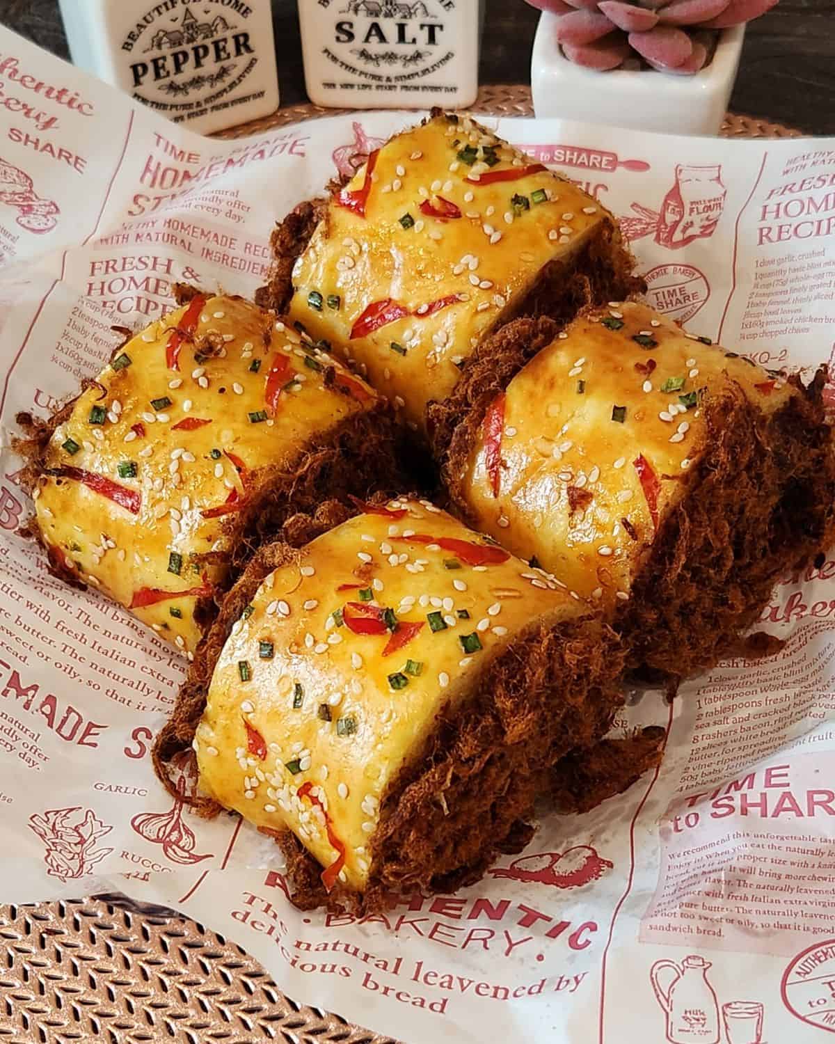 Four beef floss bread roll served on a parchment paper.