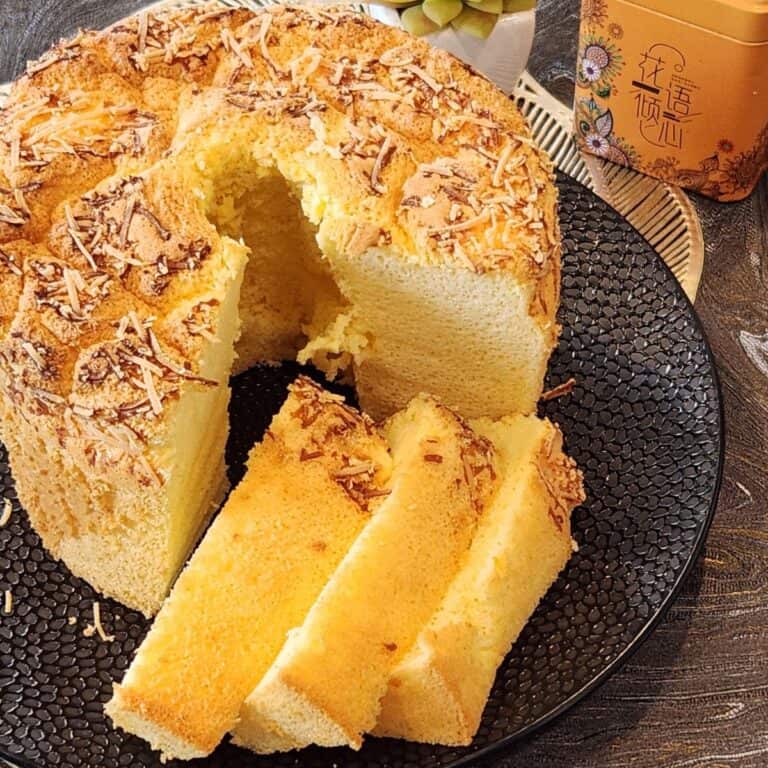 Cheese chiffon cake with a few slices on a black plate.