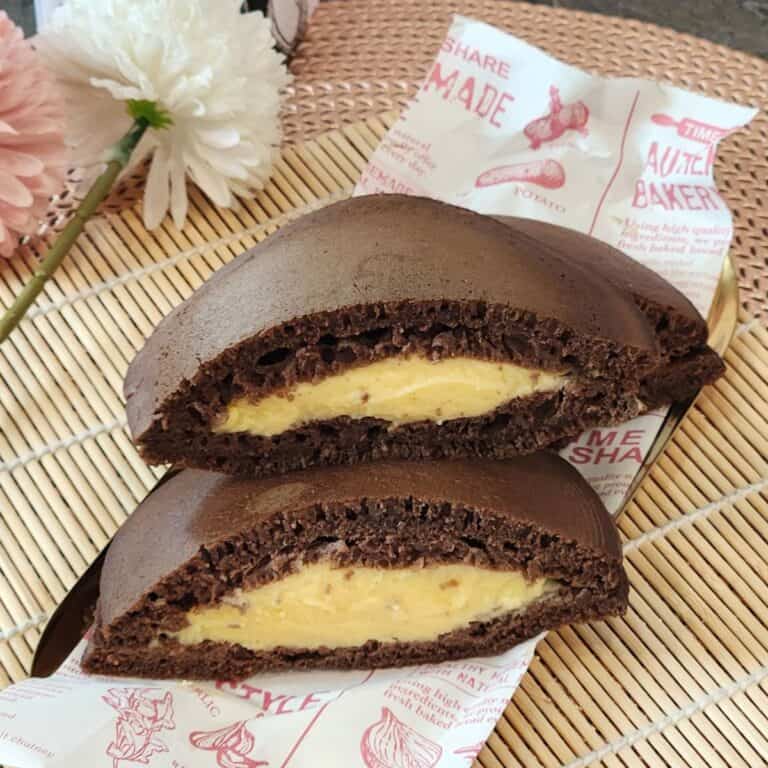 A stack of Chocolate dorayaki with custard filling on parchment paper.