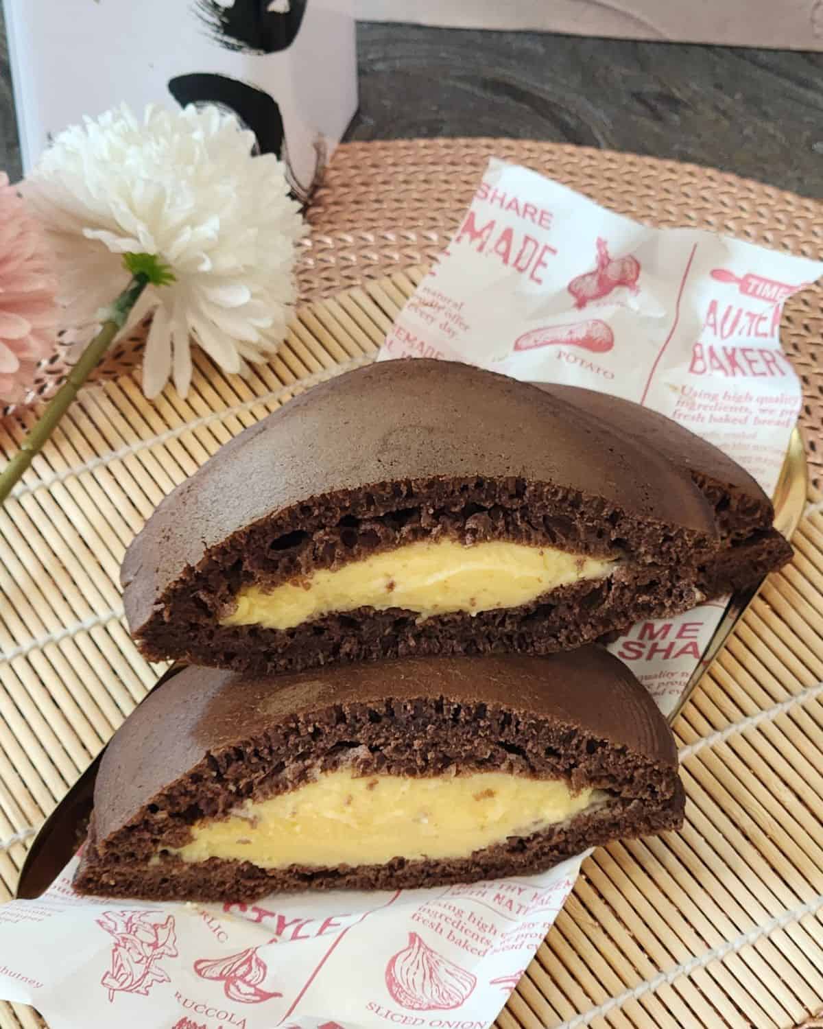 A stack of Chocolate Dorayaki with custard filling on parchment paper.