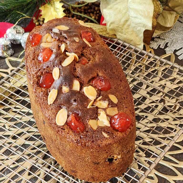 A loaf of English fruit cake on a wire rack.