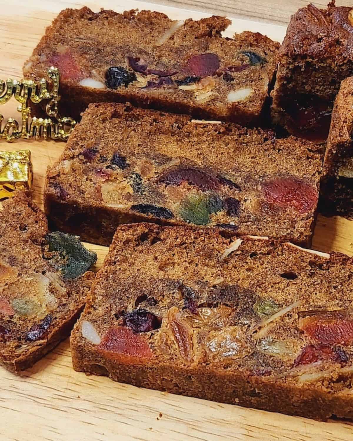 A few slices English fruit cake on a wooden board.
