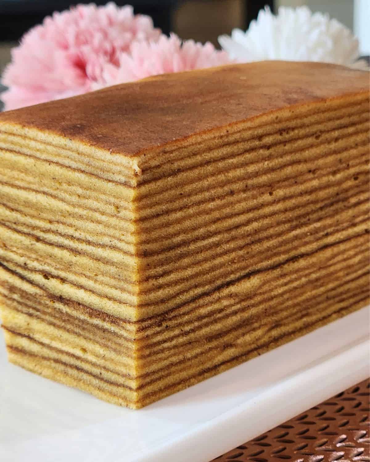 A loaf of Lapis Legit Indonesian Thousand Layers Cake on a white plate.