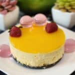 No Bake mango cheesecake decorated with jelly and strawberries on a plate.