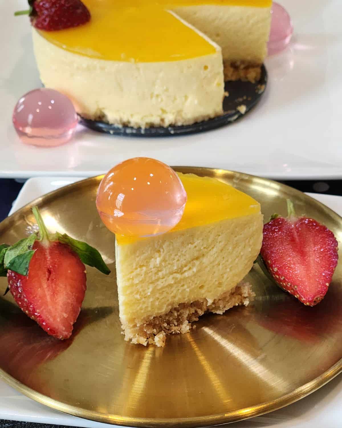 A slice of no bake mango cheesecake on a golden plate.