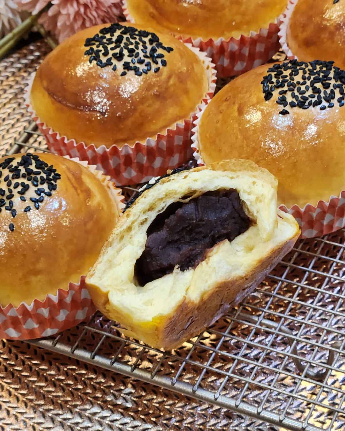 Half-eaten red bean bread or anpan on a wire rack.