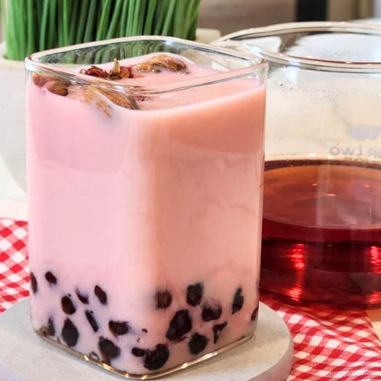 A glass of Rose milk tea with boba or tapioca pearls.