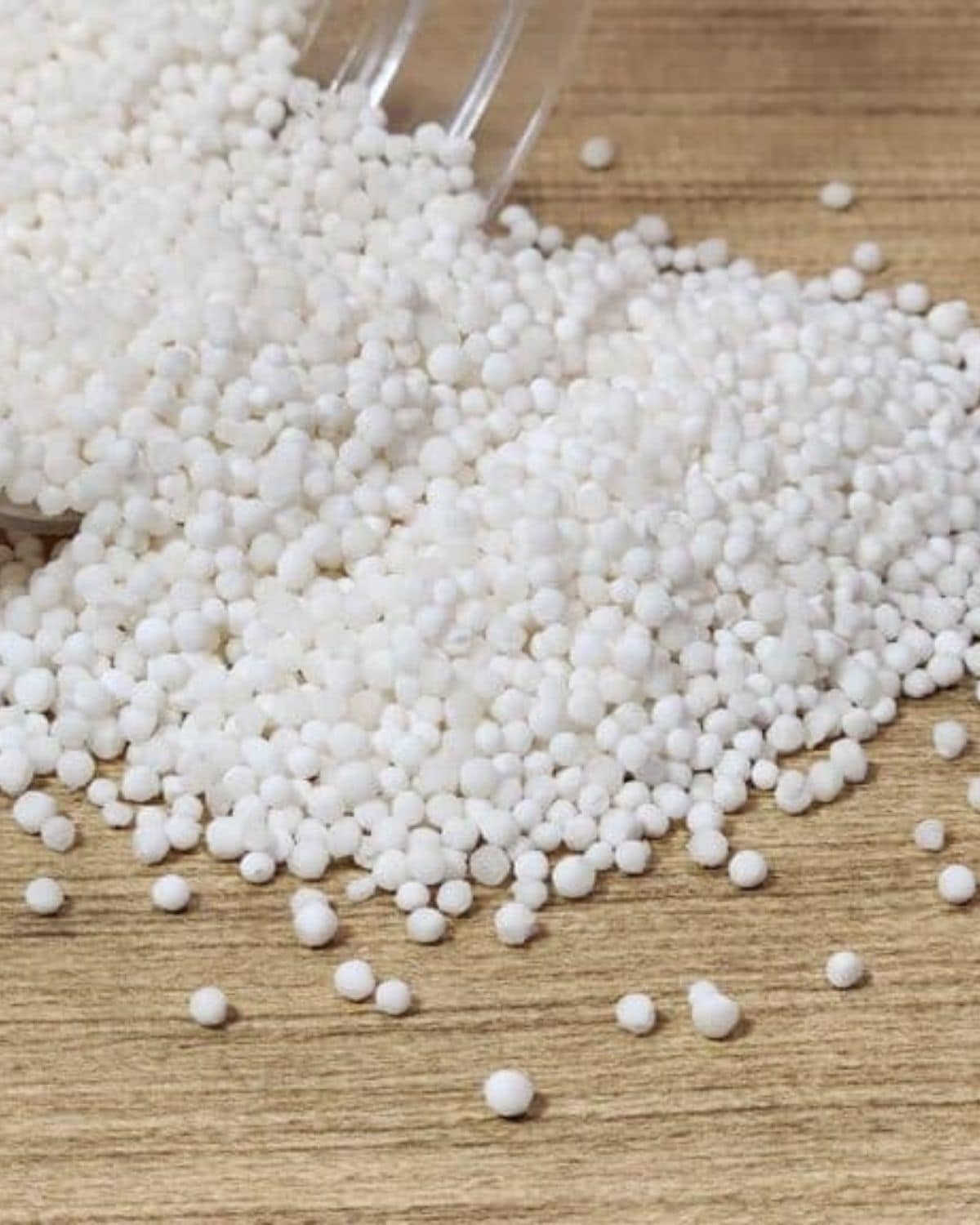 Sago pearls uncooked on a wooden table.