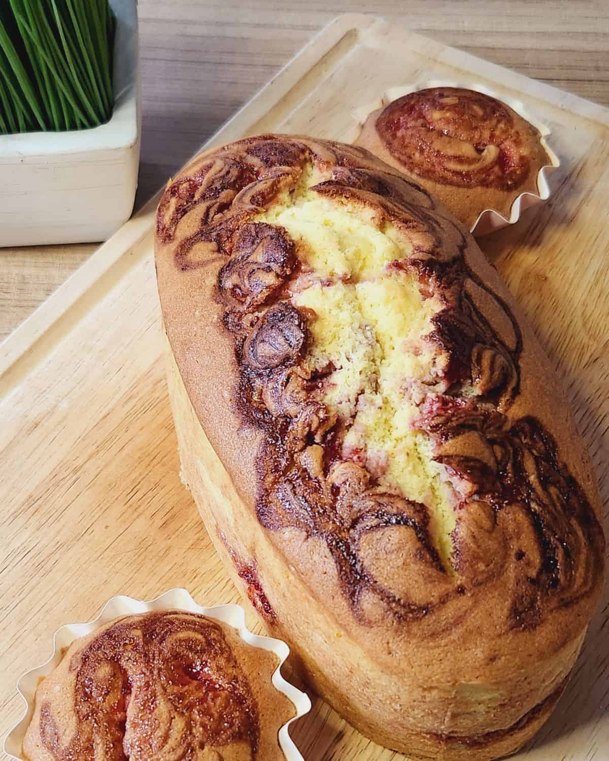 A loaf of Strawberry Cream Cheese Cake on a wooden board.