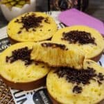 A few Thai egg cake with chocolate topping on a parchment paper, one sliced in half.