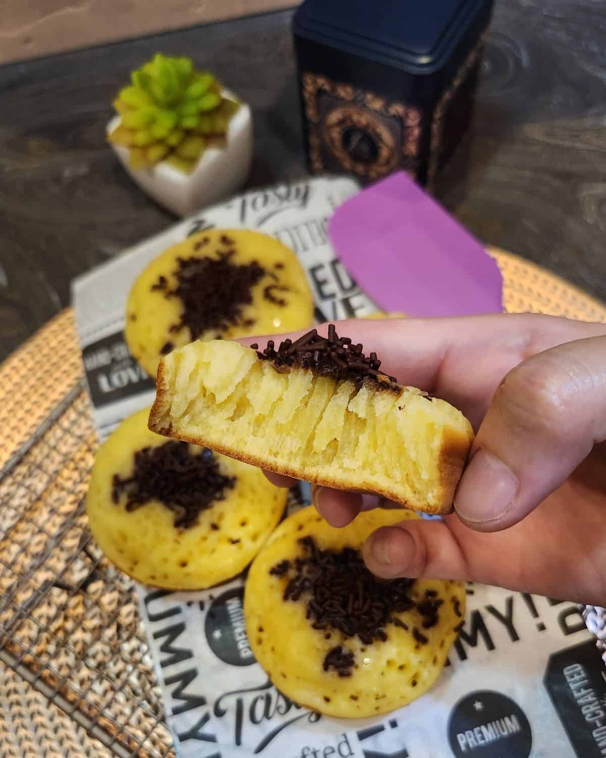 A hand holding sliced Thai egg cake showing the texture.