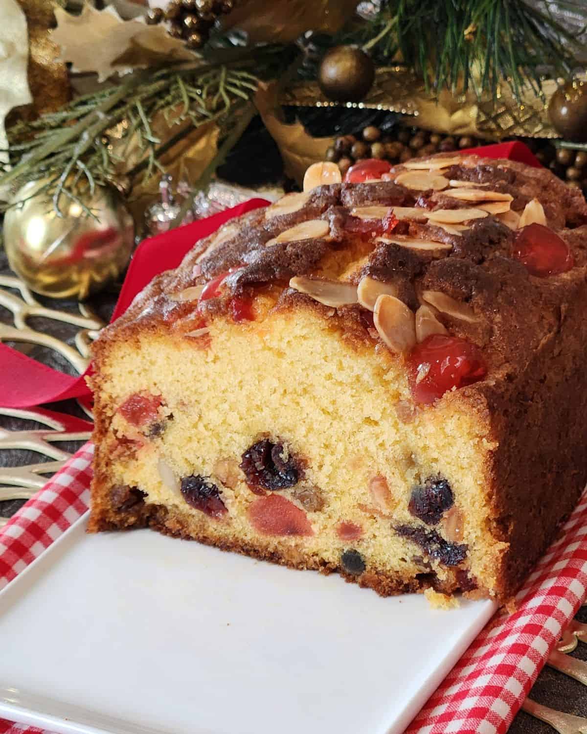 Half loaf of vanilla fruit cake on a white plate.