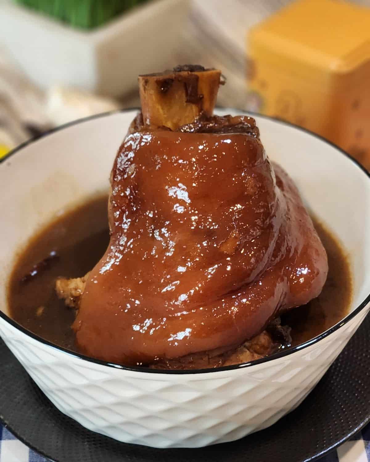 Glossy, tender braised pork shank served in a bowl.