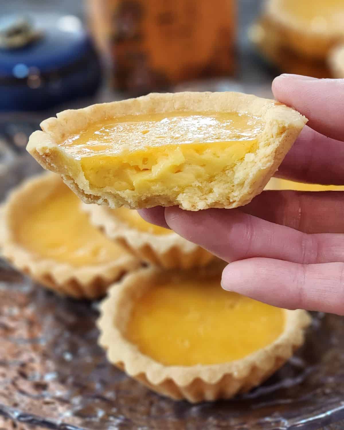 A hand holding Hong Kong custard egg tart in half. 