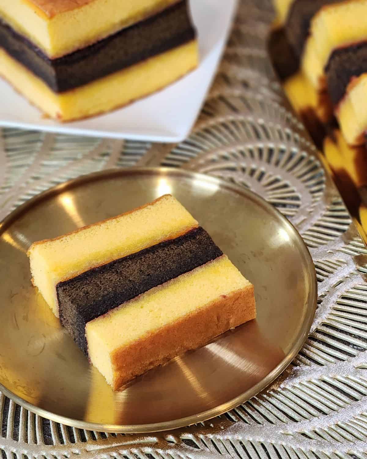 A slice of Lapis Surabaya cake on a golden plate.