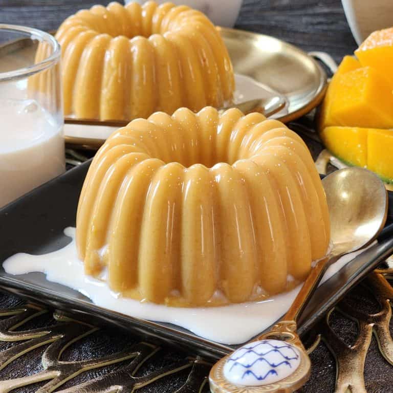 A small plate with mango pudding and evaporated milk.
