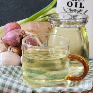 A small cup of fresh scallion oil with ingredients at the back.
