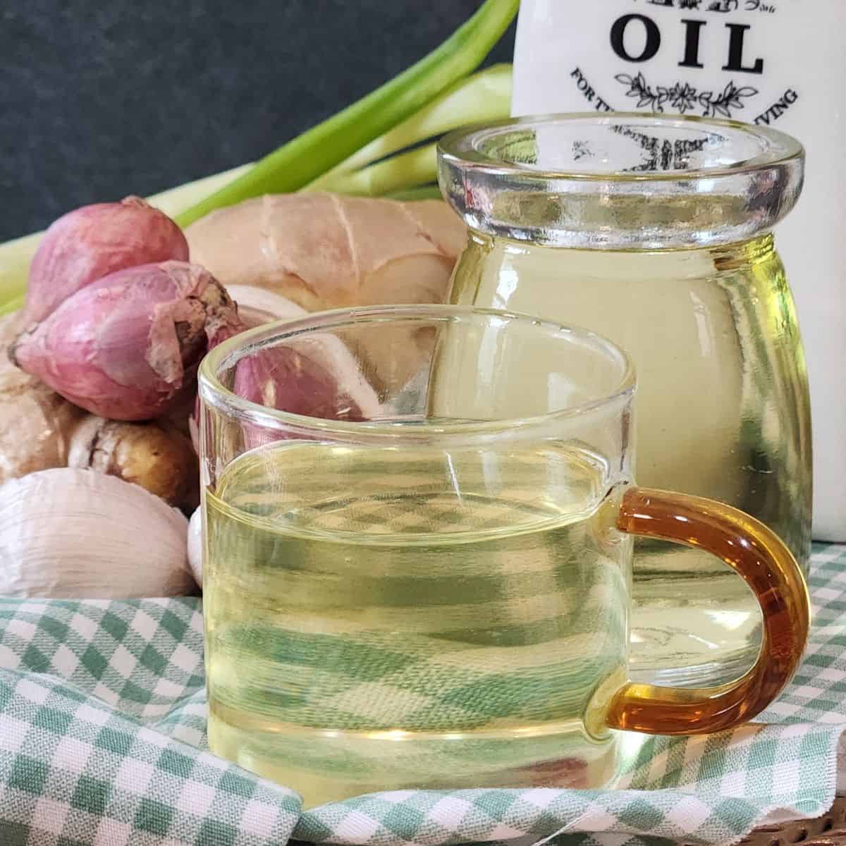 A small cup of fresh scallion oil with ingredients at the back.