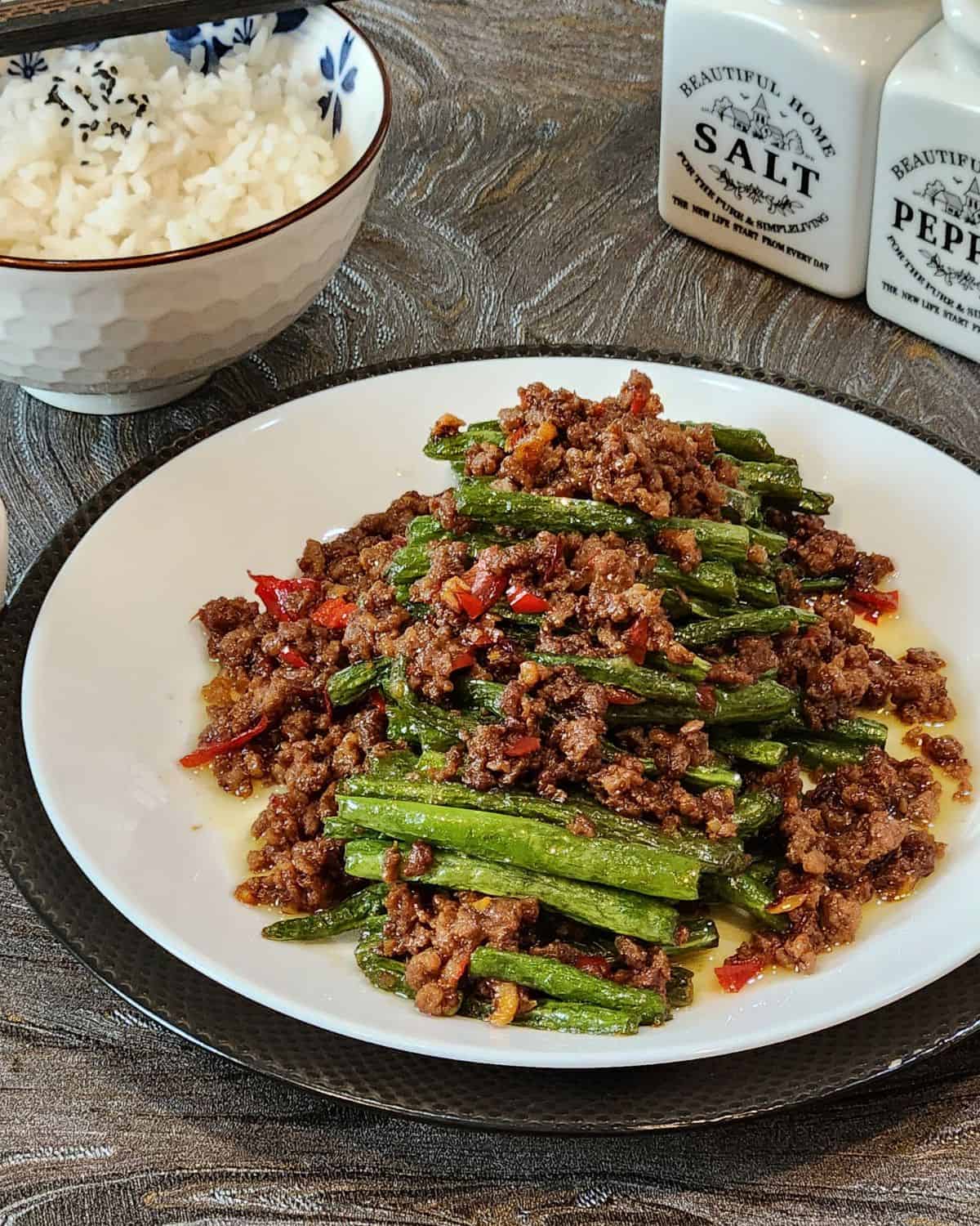 A plate of green beans and ground beef stir fry.