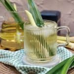 A glass of lemongrass pandan tea with pandan leaf and lemongrass stalk for decoration.