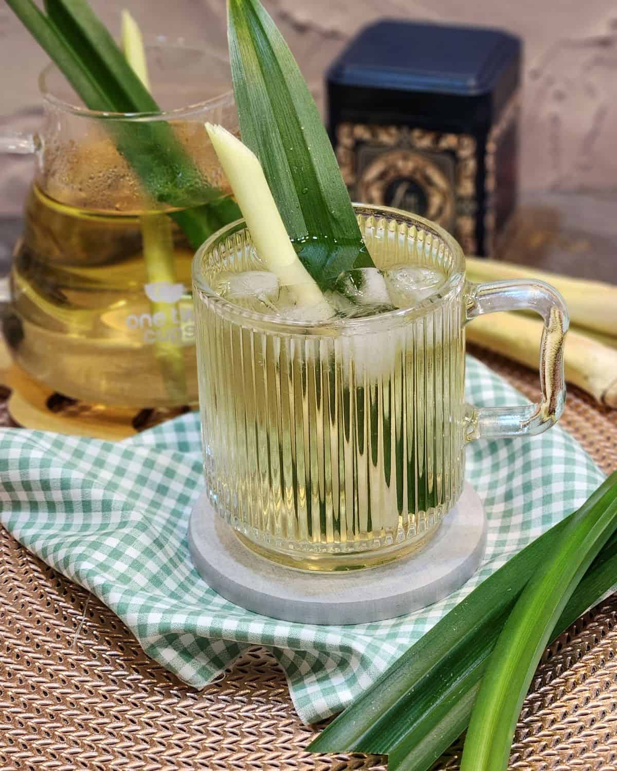 A glass of lemongrass tea with pandan leaf and lemongrass stalk for decoration. 