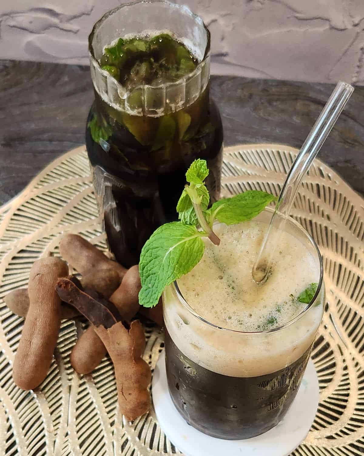 A glass of tamarind iced tea with fresh mint leaves.