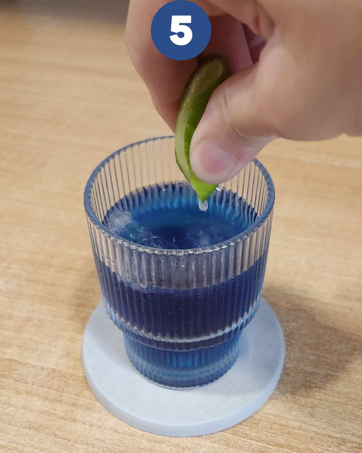 Process photo of adding lime or lemon into the butterfly pea tea.