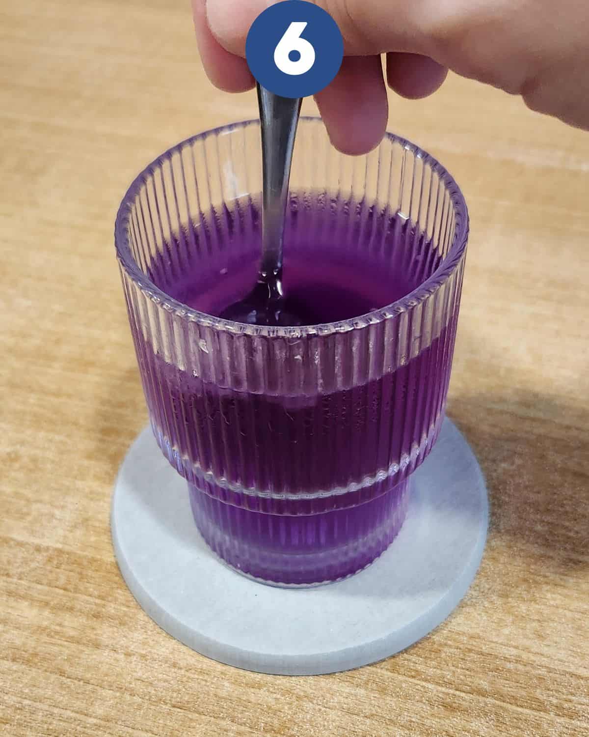 Stirring the butterfly pea tea until it changes color.