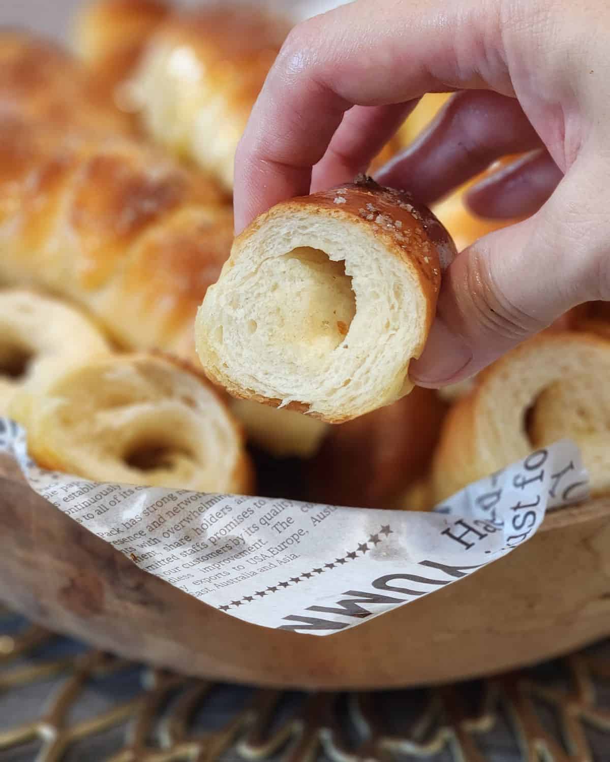 A hand holding sliced salt bread that has a hollow made by butter block.