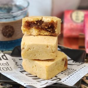 A stack of three Taiwanese pineapple cakes with pineapple jam filling inside.