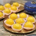 Freshly made glossy pineapple tarts arranged on a golden tray, showcasing their shiny yellow coating and soft texture, perfect for dessert or tea time.