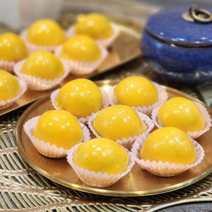 Freshly made glossy pineapple tarts arranged on a golden tray, showcasing their shiny yellow coating and soft texture, perfect for dessert or tea time.