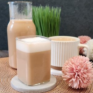A glass of warm London Fog or Earl Grey milk tea with milk froth on top.