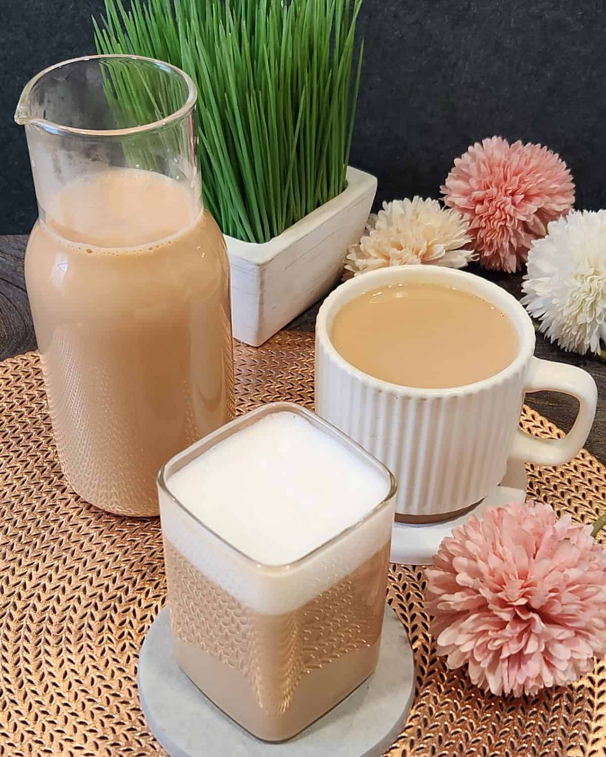 Earl grey milk tea or London fog in a glass, a cup, and a serving bottle.