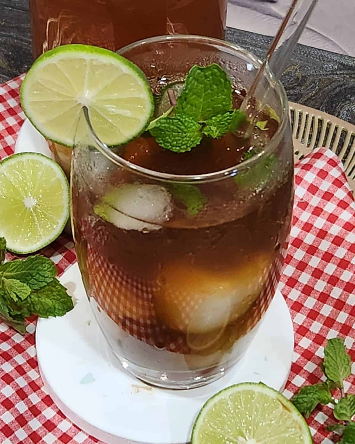 A glass of lychee tea garnished with mint leaves and lime slices.