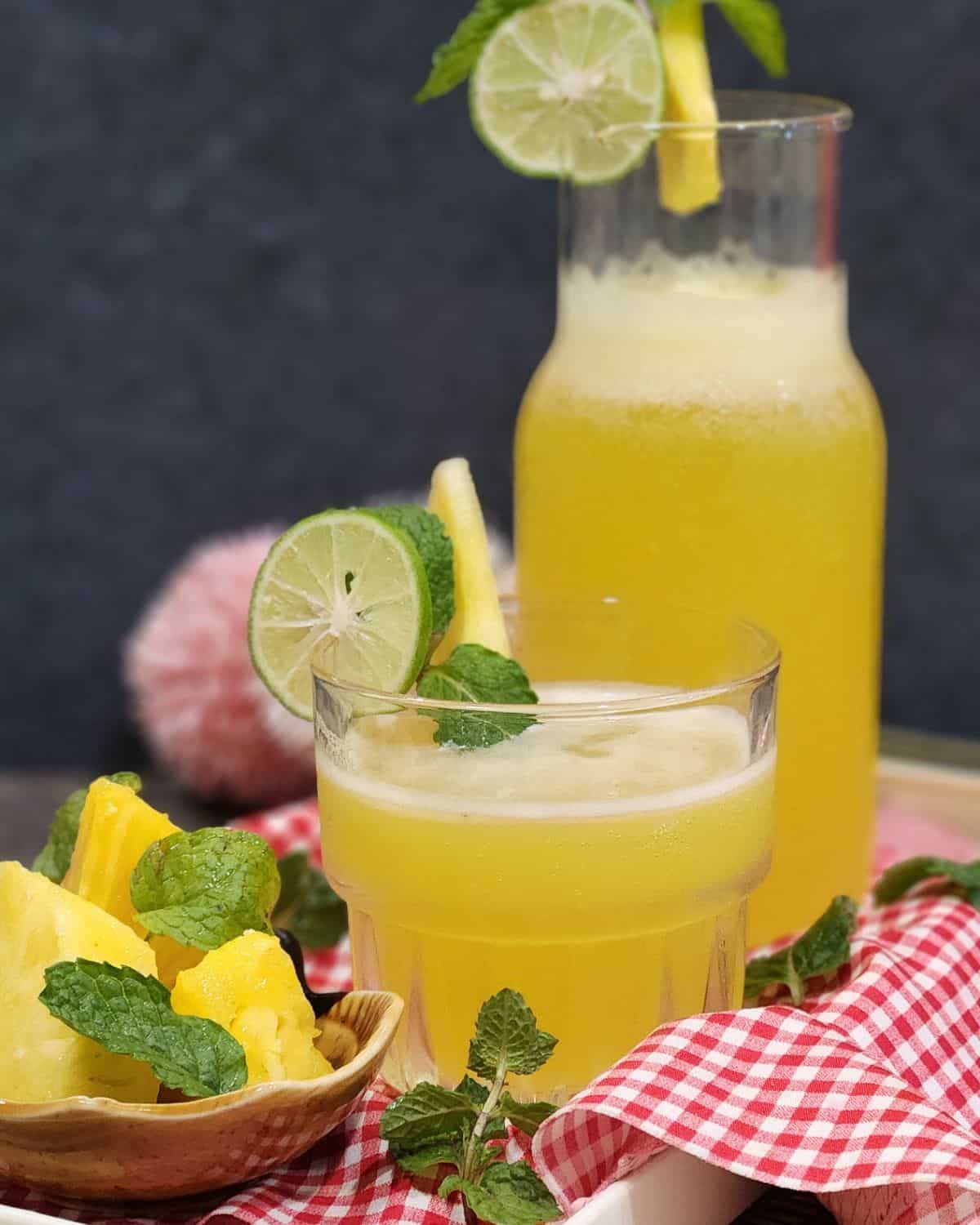 A glass of cold pineapple mint soda on a red and white cloth.