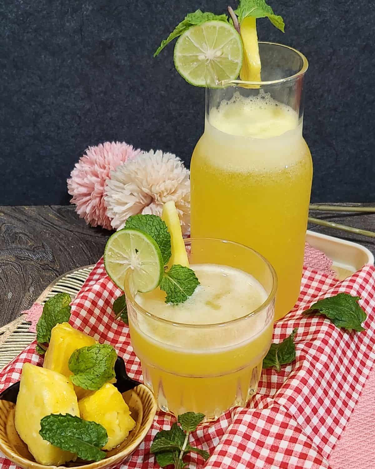 A glass and a jar of cold pineapple mint soda garnished with lime slices.