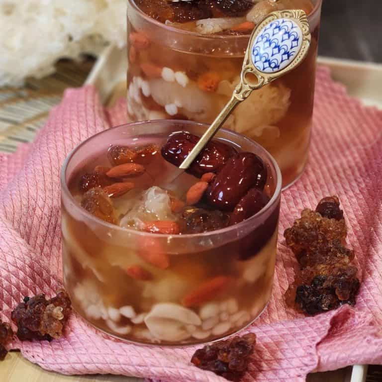 A glass of peach gum dessert (tong sui) or snow fungus dessert served cold on a tray.