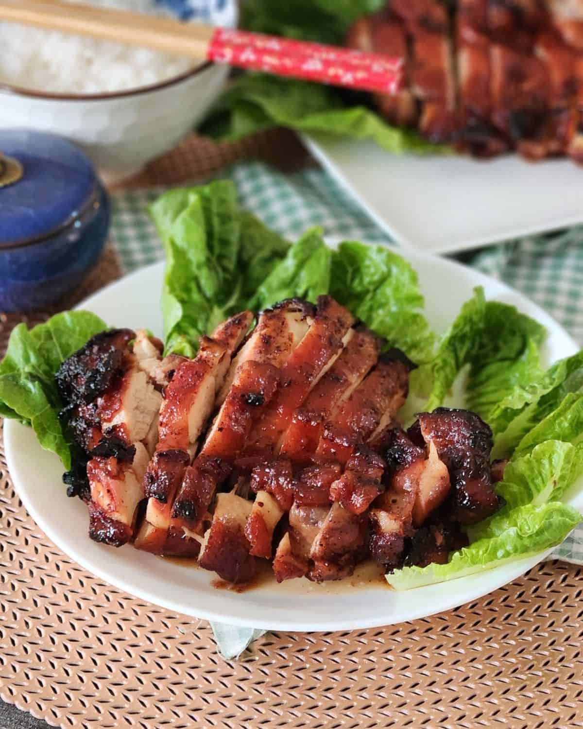 Air fryer char siu chicken on a plate garnished with green vegetables.