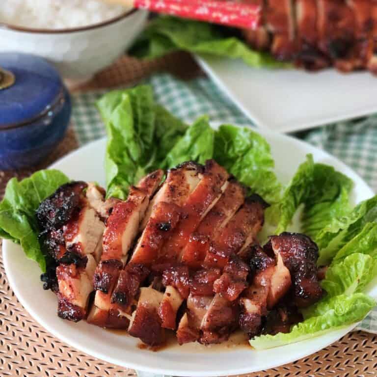 Air fryer char siu chicken on a plate with some green vegetables.