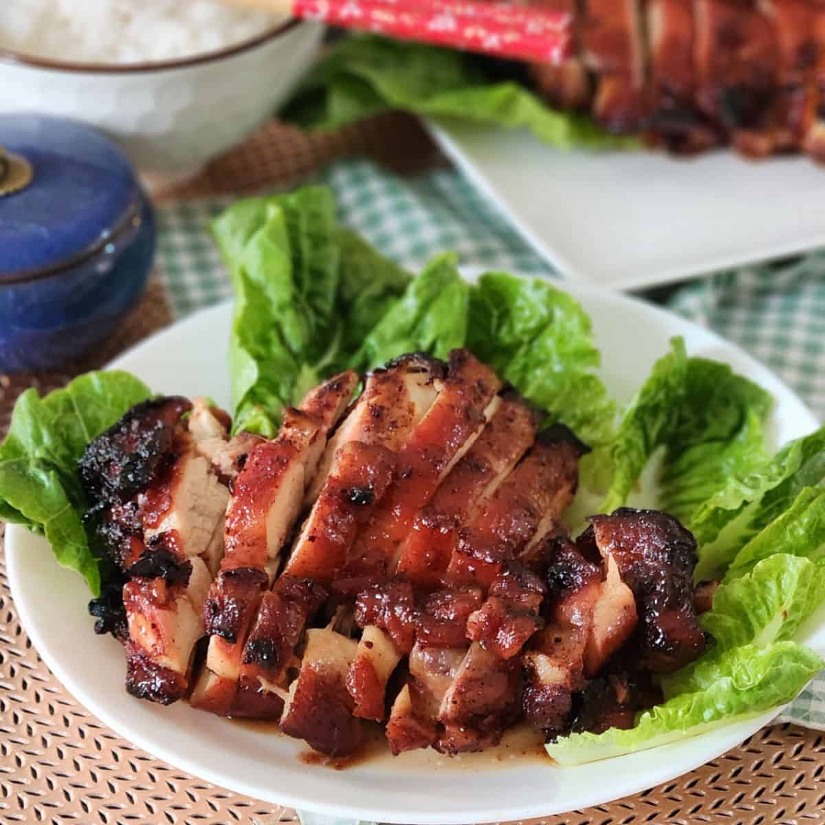 Air fryer char siu chicken on a plate with some green vegetables.