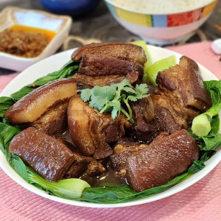 A big bowl of Chinese braised pork belly with blanched bok choy and steamed rice at the back.