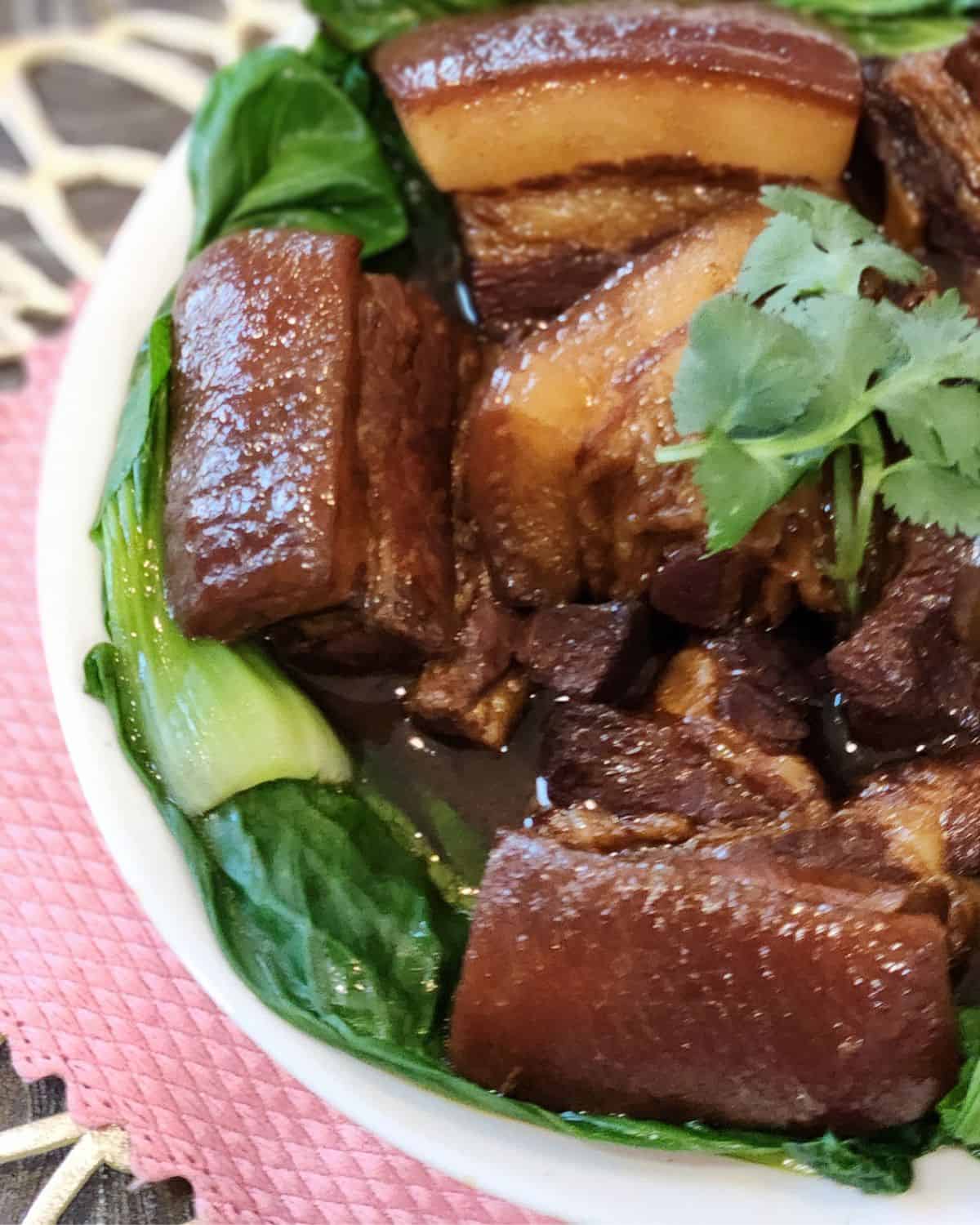 A bowl of braised pork belly with blanched bok choy.