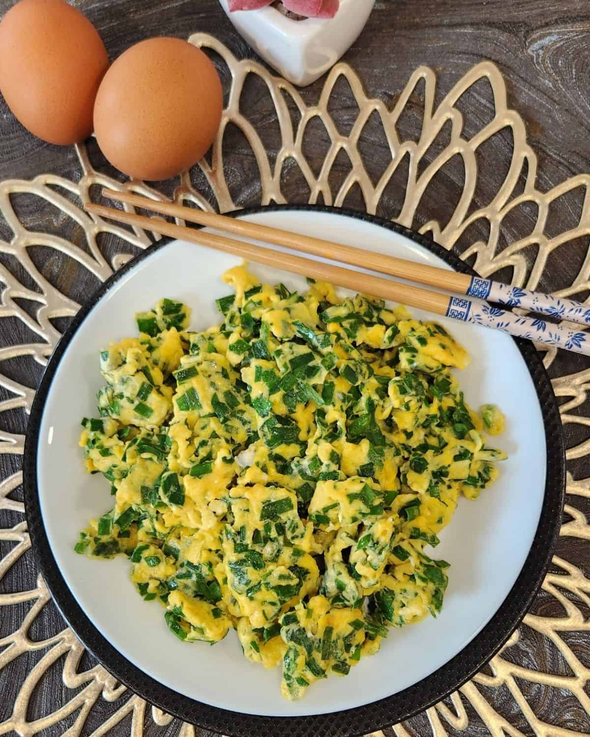 A plate of chive scrambled eggs with chopsticks.