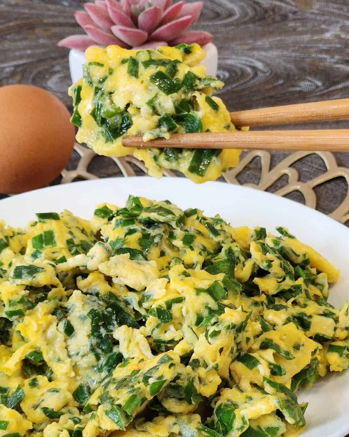 A pair of chopsticks holding Chinese chive scrambled eggs. 