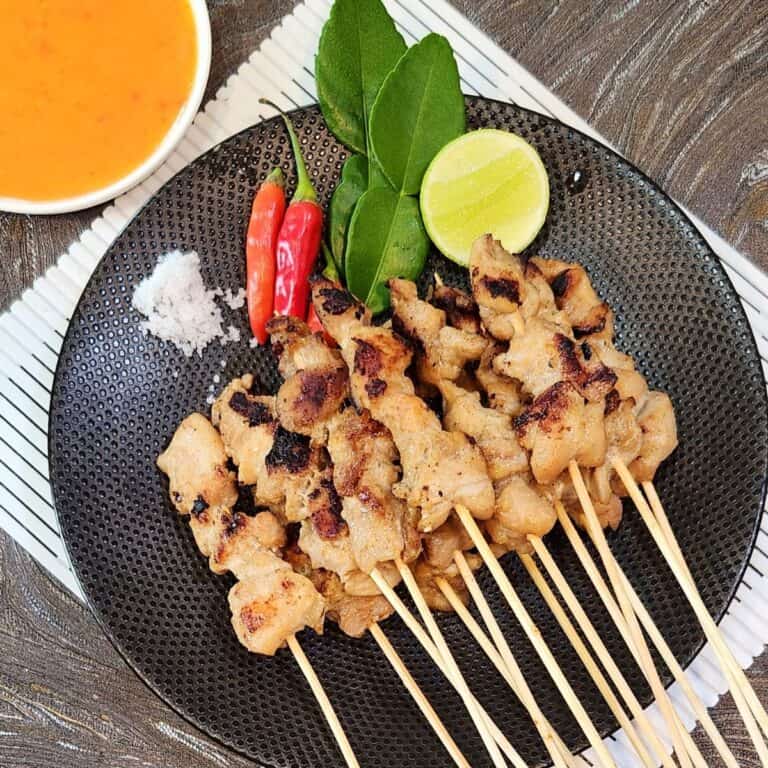 A plate of Sate Taichan with chili, a pinch of salt, and lime wedge.